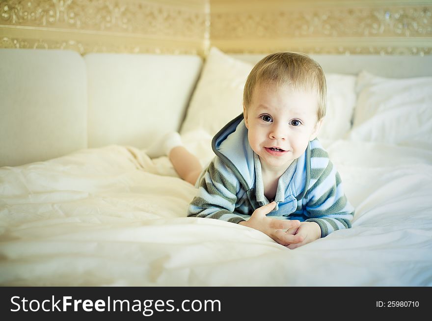 The child in a pajamas on a bed lies. The child in a pajamas on a bed lies