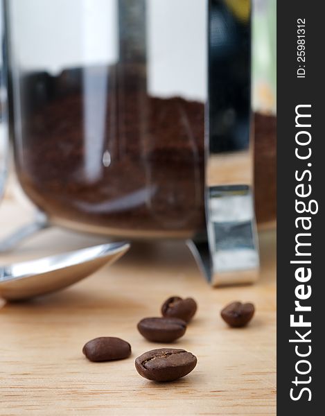 Close focus on coffee beans in front of french press and spoon. Close focus on coffee beans in front of french press and spoon