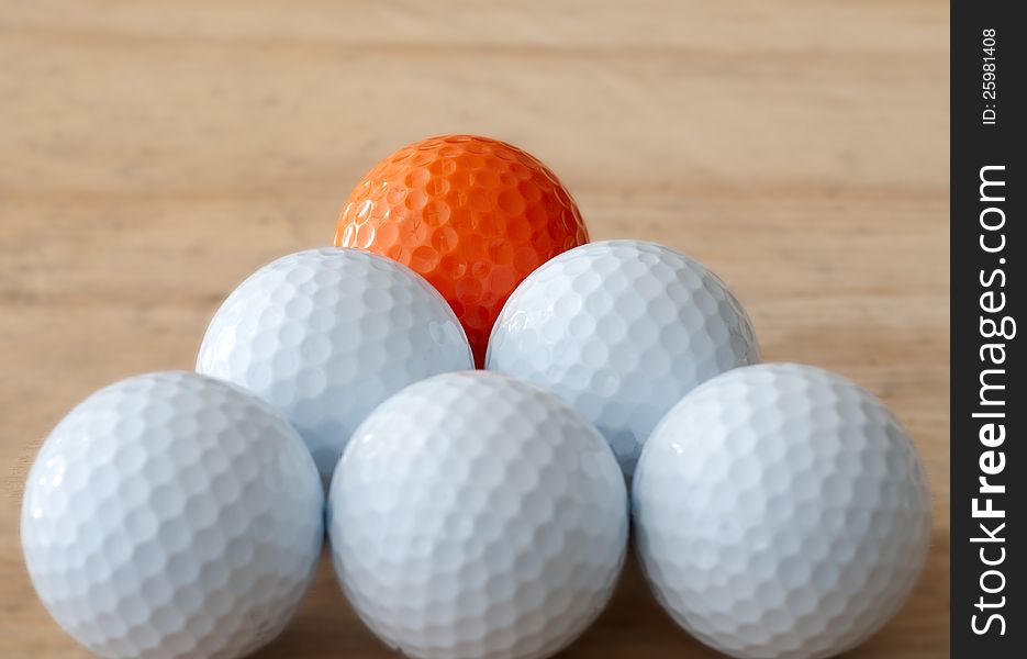 One orange golf ball in still life with white golf balls. One orange golf ball in still life with white golf balls