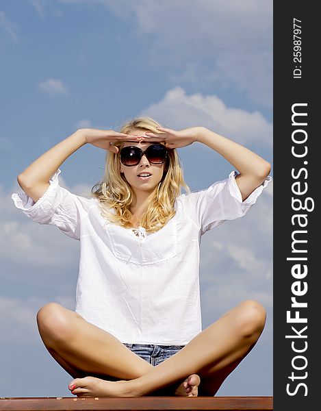 Portrait of beautiful blonde girl in sunglasses on background blue sky. Portrait of beautiful blonde girl in sunglasses on background blue sky