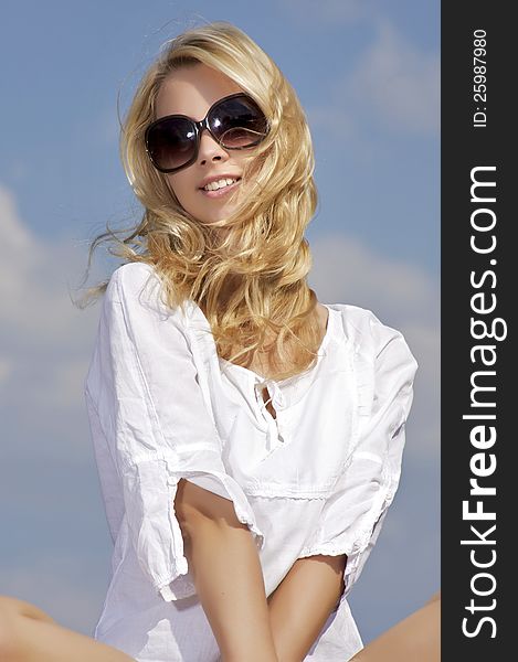 Portrait of beautiful blonde girl in sunglasses on background blue sky. Portrait of beautiful blonde girl in sunglasses on background blue sky