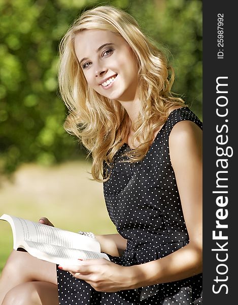 Young attracive blone woman reading book in park outdoor. Young attracive blone woman reading book in park outdoor