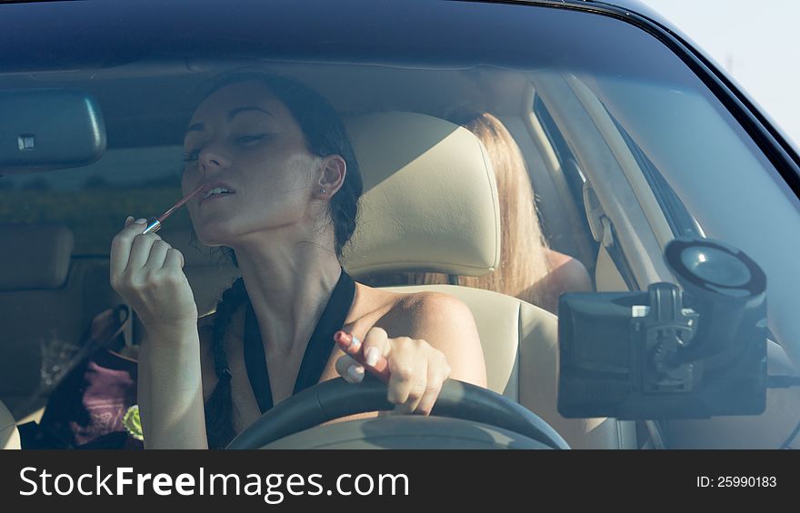 Woman driver applying lipstick