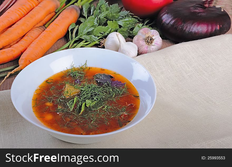 A bowl of vegetable soup with fresh ingredients against