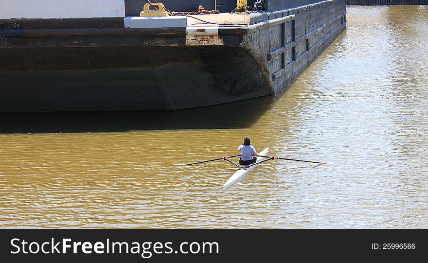 Female rower on the river, facing a challenge when she comes upon a barge standing in her way. Female rower on the river, facing a challenge when she comes upon a barge standing in her way.