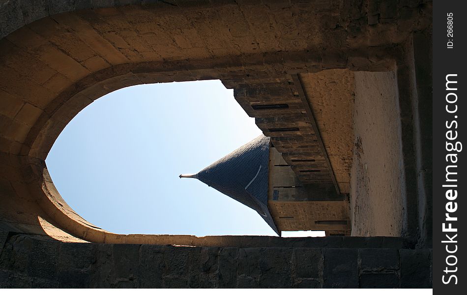 View at Carcassonne castle tower through an old stone archway in a sunny summer day with a clear blue sky. View at Carcassonne castle tower through an old stone archway in a sunny summer day with a clear blue sky