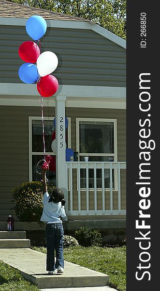 A little girl with balloons approaching her new house. A little girl with balloons approaching her new house