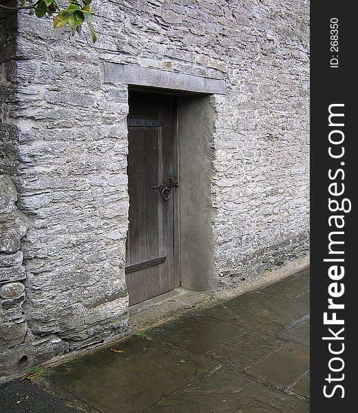 Old wooden door, set against a thick stone wall on a path near Buckfast Abbey in Devon, England. Old wooden door, set against a thick stone wall on a path near Buckfast Abbey in Devon, England