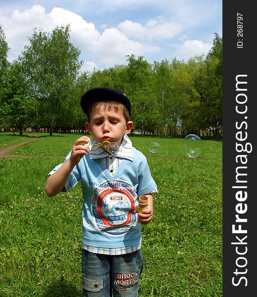 The boy and soap bubbles in park
