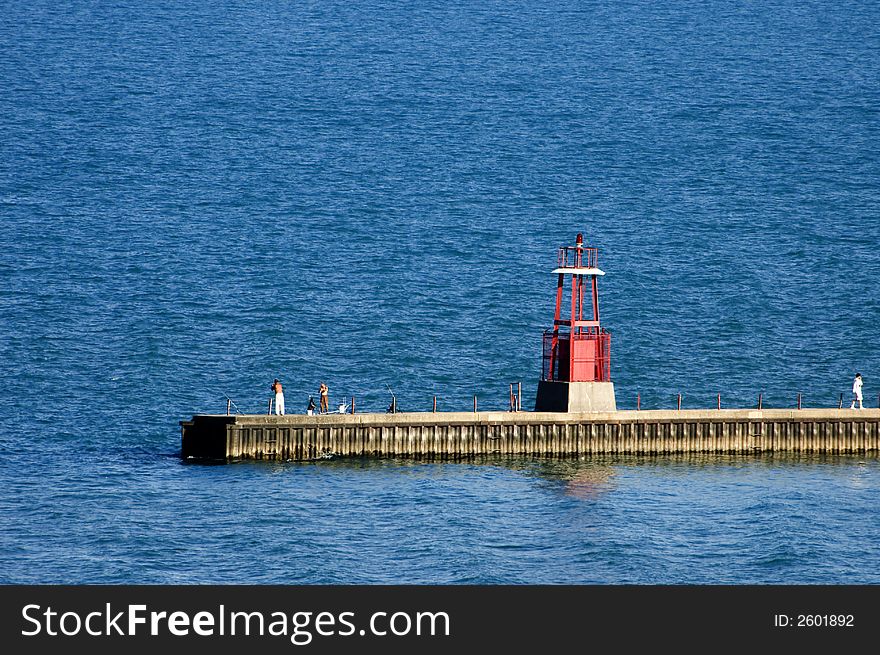 Several people fishing on a pier on Lake Michigan