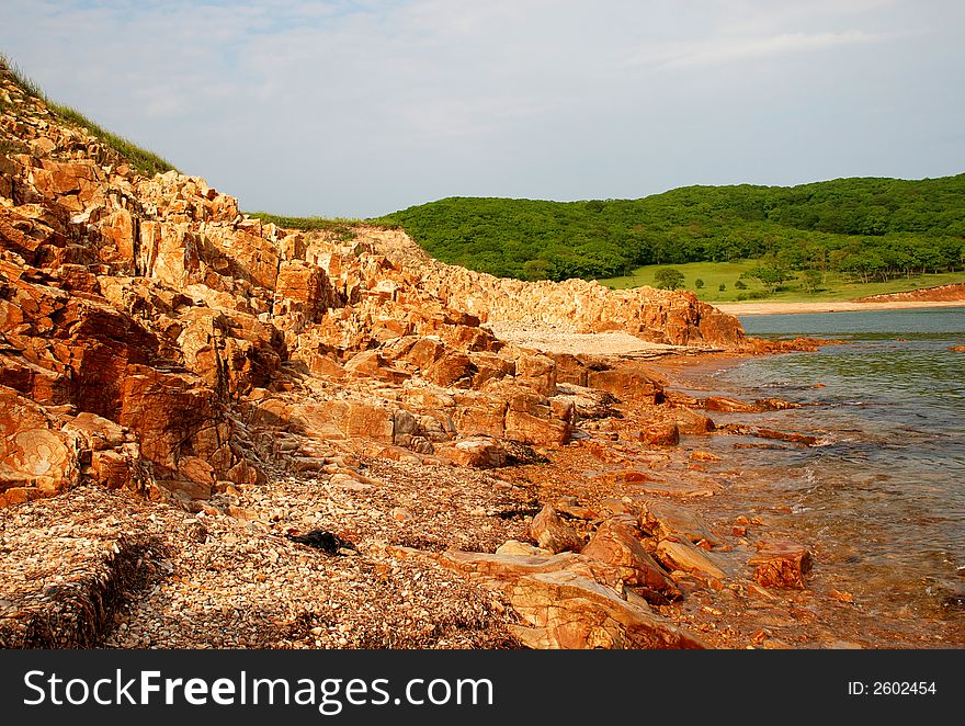 Red rocks, coast of the Pacific ocean, sea, stone beach, landscape, view, summer. Red rocks, coast of the Pacific ocean, sea, stone beach, landscape, view, summer