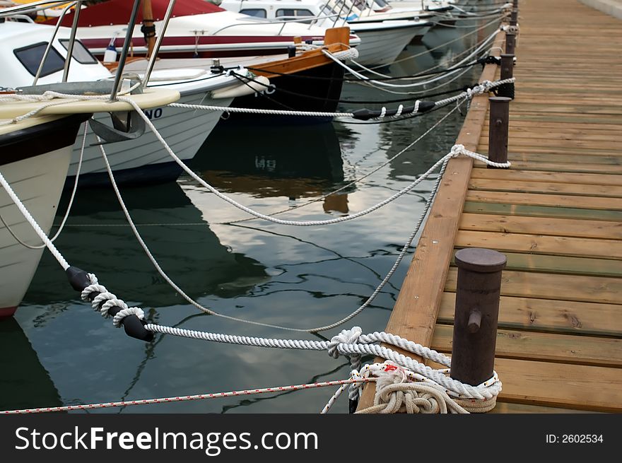 Boats tied on wooden dock in harbor