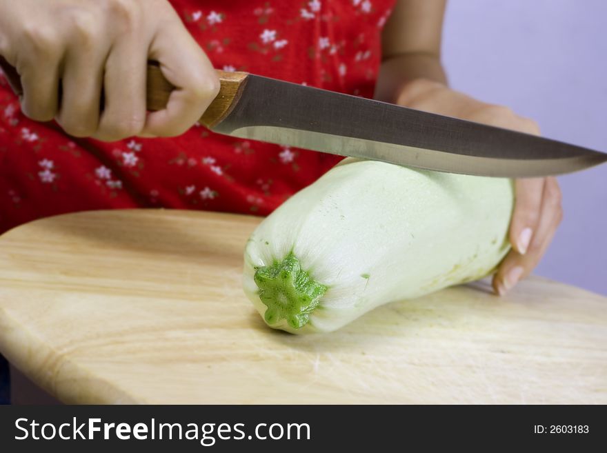 Girl cutting vegetable marrow on wood