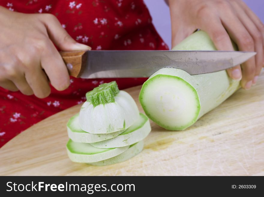 Girl cutting vegetable marrow on wood