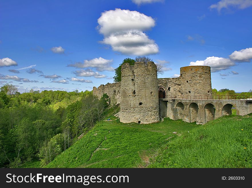 Medieval castle and green trees under blue sky with clouds. Medieval castle and green trees under blue sky with clouds