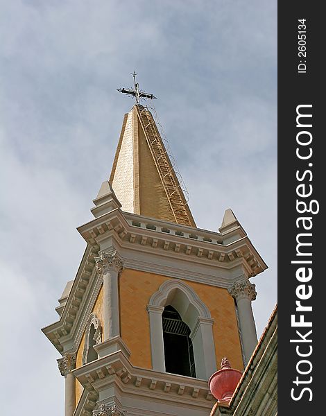 Gold steeple of Catholic church against cloudy sky. Gold steeple of Catholic church against cloudy sky