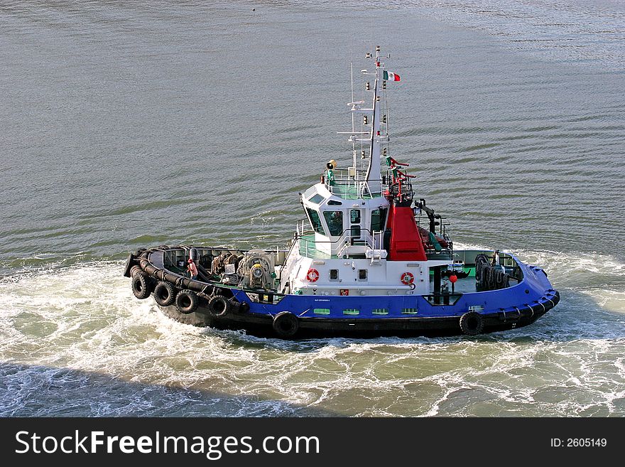 A tugboat moving through the water at a port. A tugboat moving through the water at a port