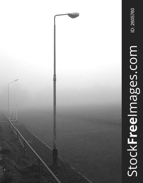 An on street lamp in fog near a running track. An on street lamp in fog near a running track