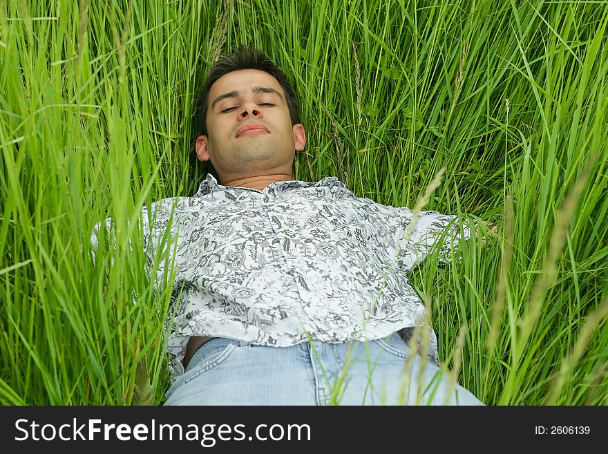 Boy relaxing in high green grass with closed eyes. Boy relaxing in high green grass with closed eyes