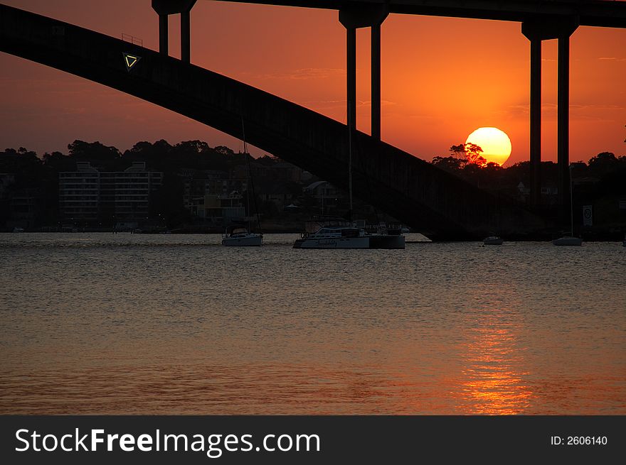 A red setting sunset view through arched bridge segment. A red setting sunset view through arched bridge segment