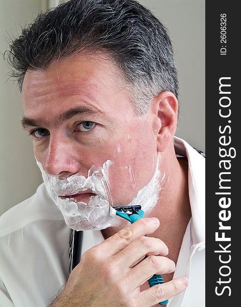 Man shaving trying to get ready for work.