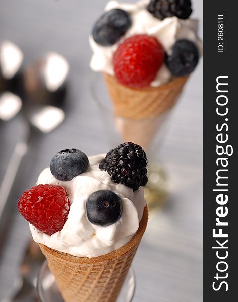 Two waffle cones with whipped cream and berries