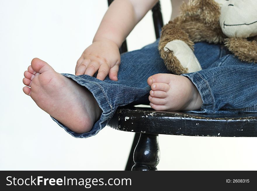 Image of a toddler sitting on a black chair, only his lower body visible. Image of a toddler sitting on a black chair, only his lower body visible