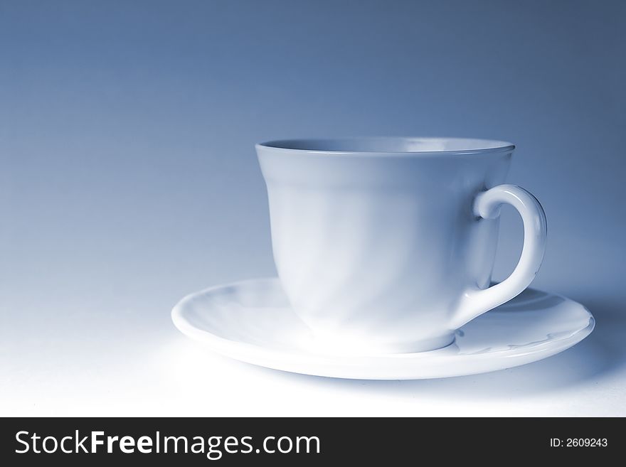 White mug of coffee on a white background, with the admixture of blue tones