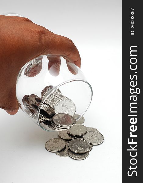 Coins spilling from the glass isolated on white background