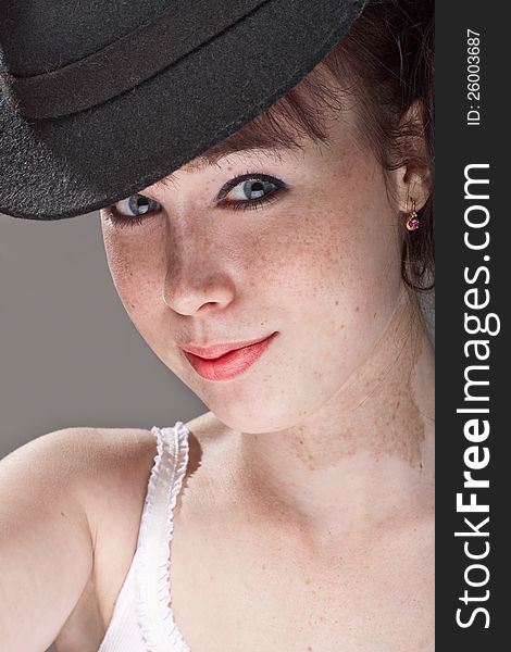 Close-up portrait of a beautiful girl with freckles and black hat. Close-up portrait of a beautiful girl with freckles and black hat