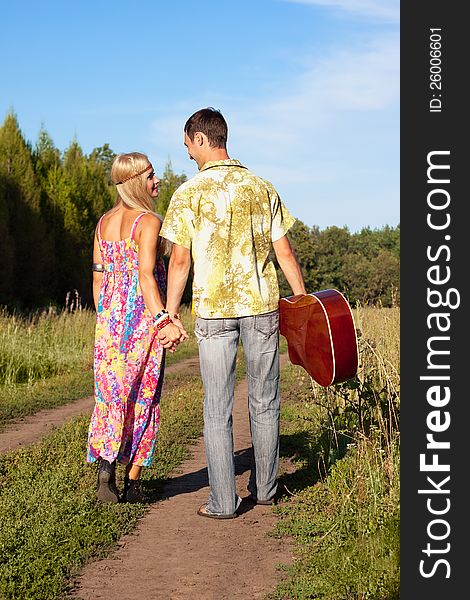 Young Woman And Man With Guitar Go On Road