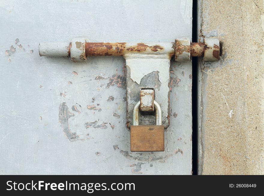 Rusty door latch with padlock of metal door