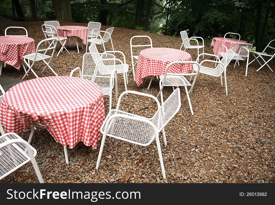 Few empty restaurant tables and chairs between trees. Few empty restaurant tables and chairs between trees