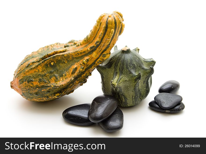 Pumpkins and black stones on white background