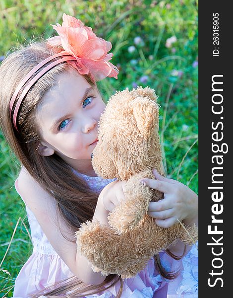 Happy little girl hugging a teddy bear against summer nature. Happy little girl hugging a teddy bear against summer nature.