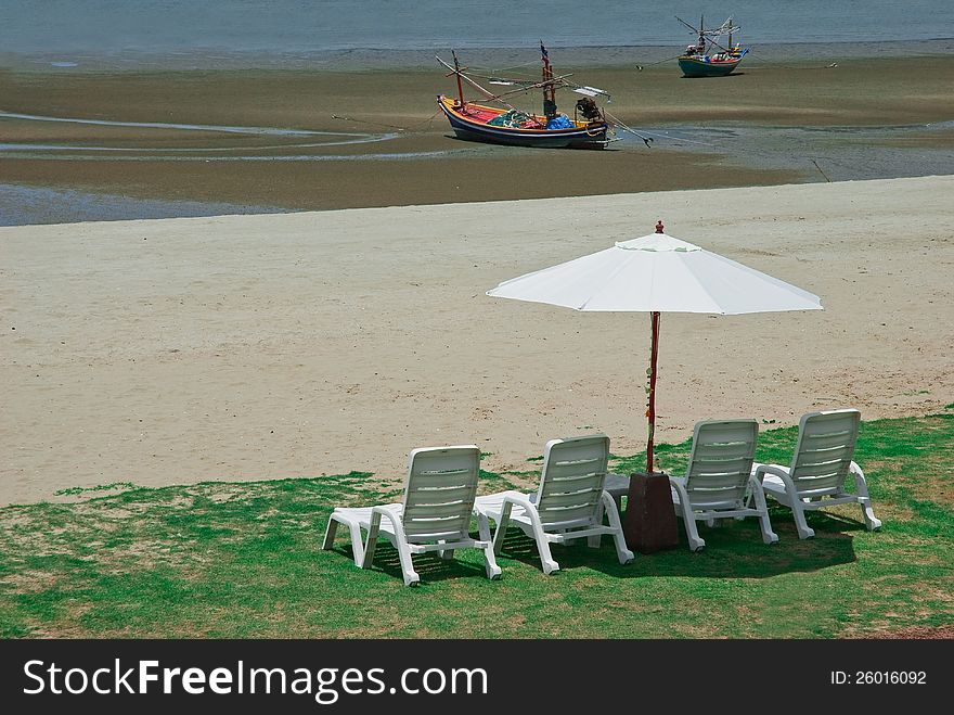 THE CHAIRS AND UMBRELLA ON GREEN GRASS AT SEASHORE