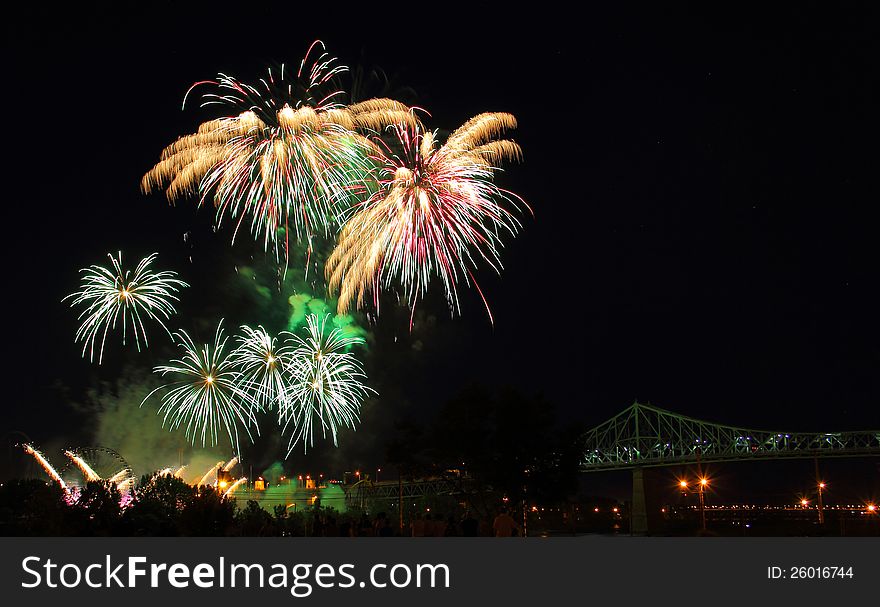 Multiple colorful Firework Bursts over a bridge with crowd of people watching. Multiple colorful Firework Bursts over a bridge with crowd of people watching