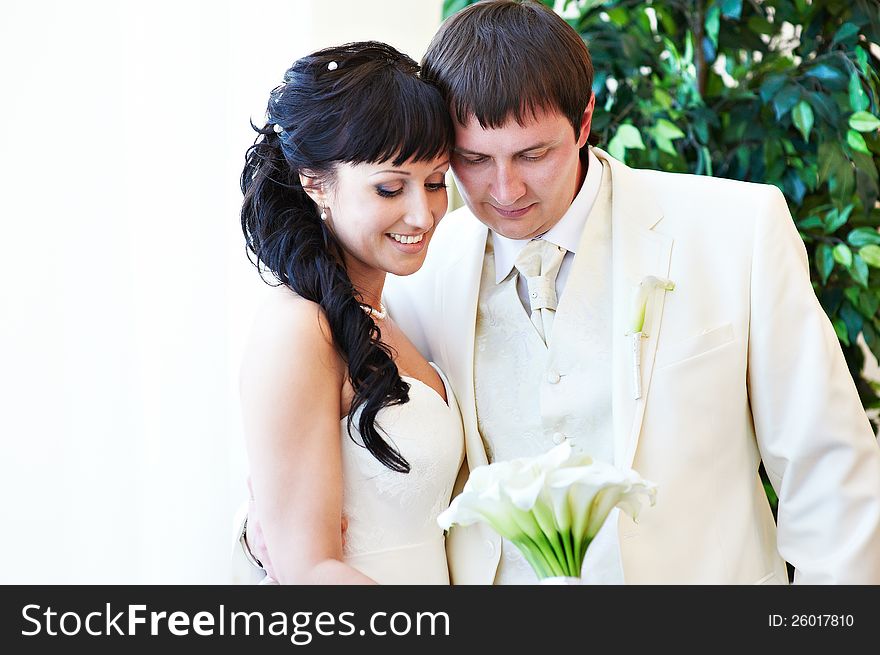 Happy bride and groom look at bouquet in wedding day