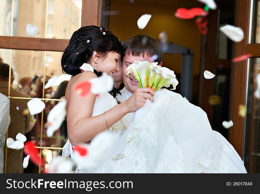 Happy newlyweds and flying red and white petals. Happy newlyweds and flying red and white petals