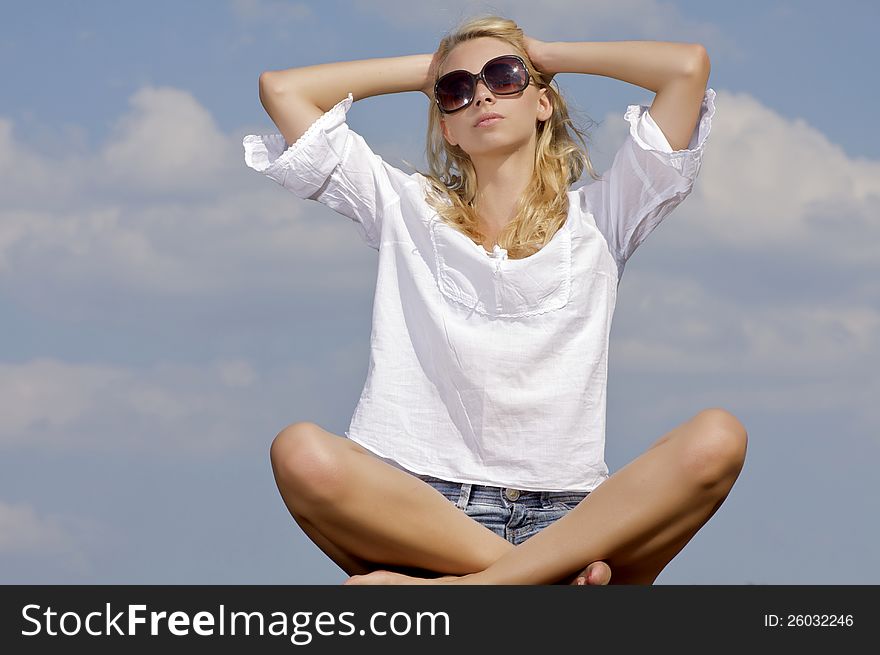 Portrait of beautiful blonde girl in sunglasses on background blue sky. Portrait of beautiful blonde girl in sunglasses on background blue sky