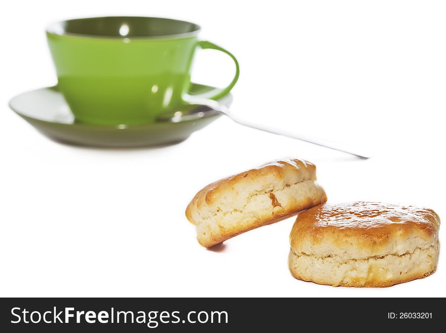 Closeup of two buttery scones with tea cup on background isolated on white. Selective focus on foreground. Closeup of two buttery scones with tea cup on background isolated on white. Selective focus on foreground