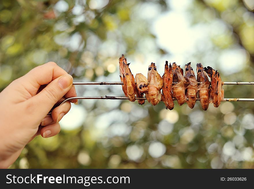 The hand of the person holds on skewers fried shrimps. The hand of the person holds on skewers fried shrimps