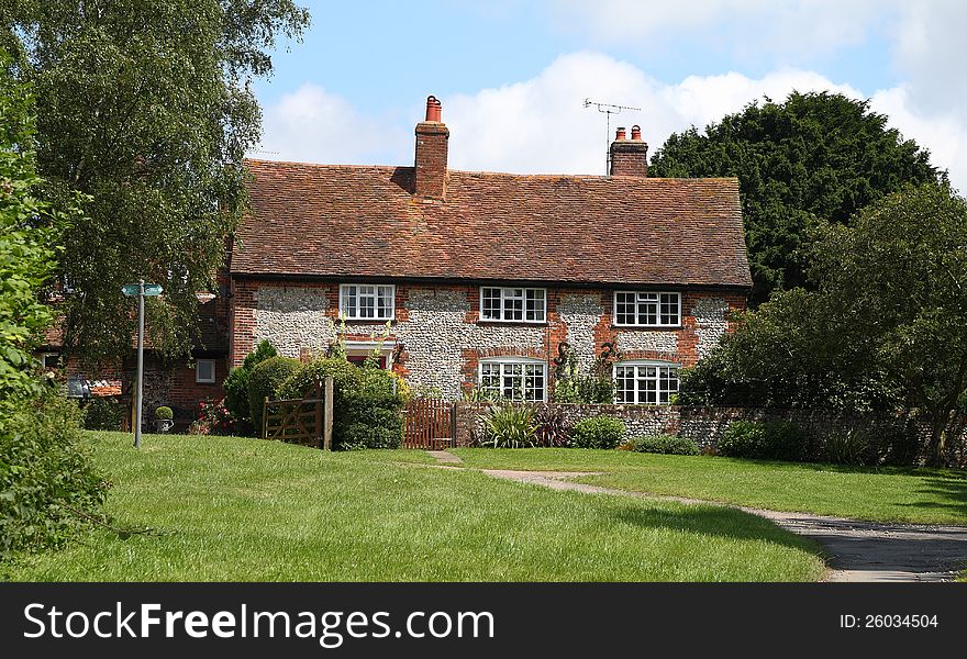 A Traditional English rural Brick and Flint House with footpath sign in front. A Traditional English rural Brick and Flint House with footpath sign in front