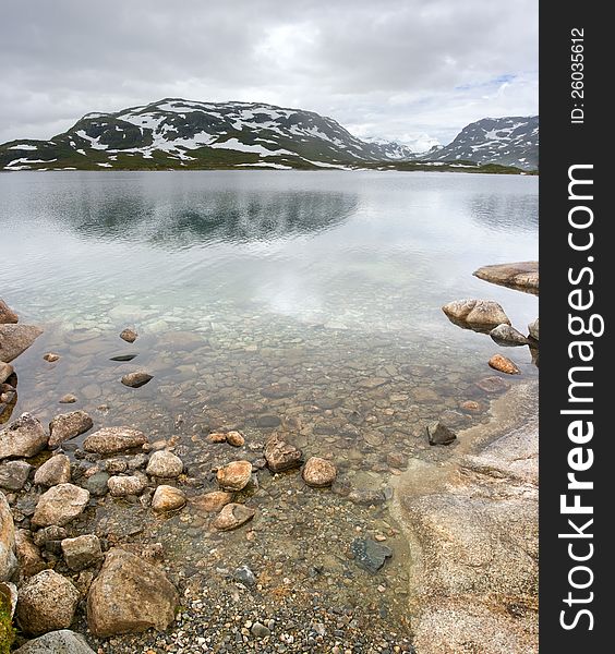 Norwegian landscape with a mountain on background and mountain lake