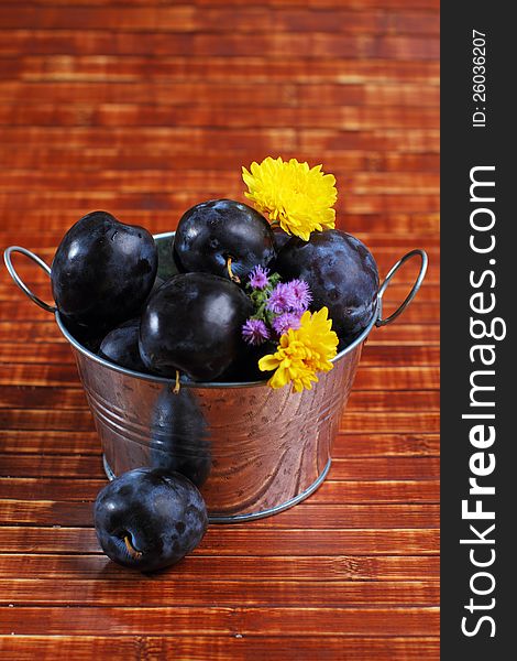 Fresh ripe plums in a tin bowl on rustic decor