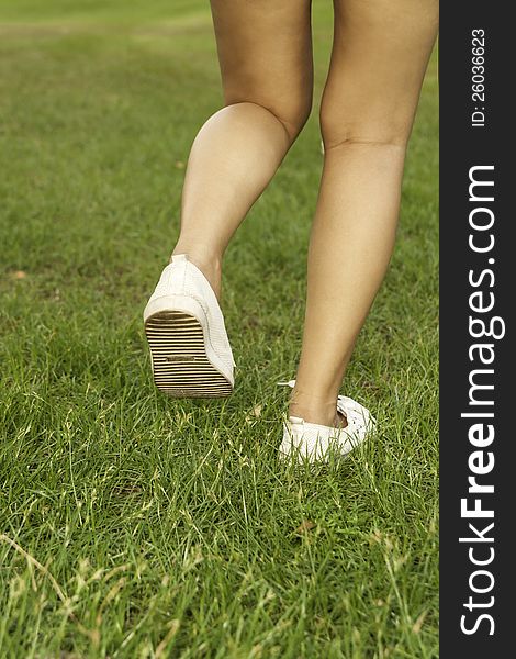 Running sport Girl runner legs and shoes in action on grass outdoors at sunset. Female athlete model.