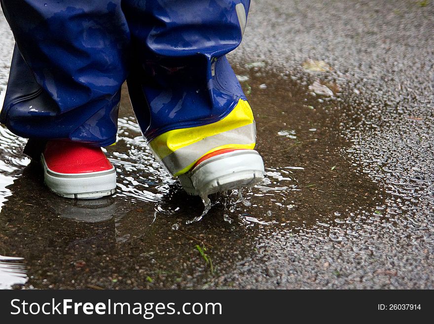 Child with gumboots splashing in a puddle. Child with gumboots splashing in a puddle