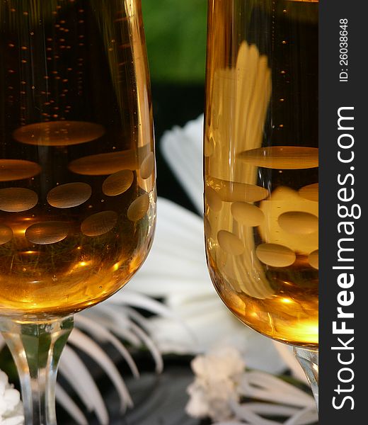 Two glasses of sparkling wine with white flowers on black