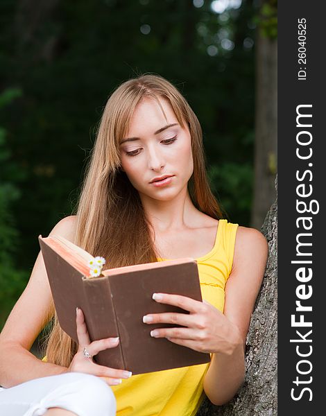 Young woman sitting near the tree and reading a book. Macro. Young woman sitting near the tree and reading a book. Macro