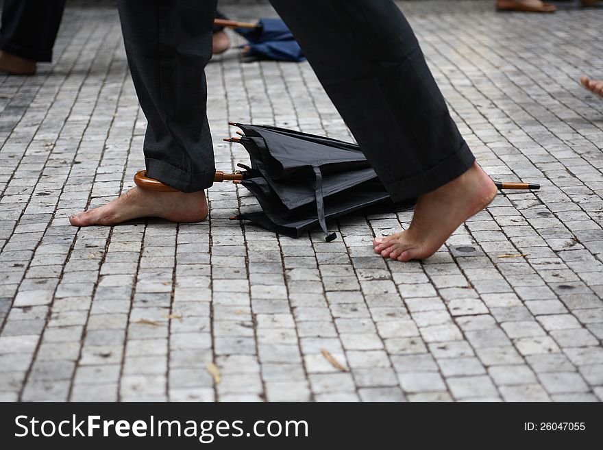 Closeup of barefoot peoples with attached umbrellas on pavement. Good Illustration for jobless or weather. Closeup of barefoot peoples with attached umbrellas on pavement. Good Illustration for jobless or weather